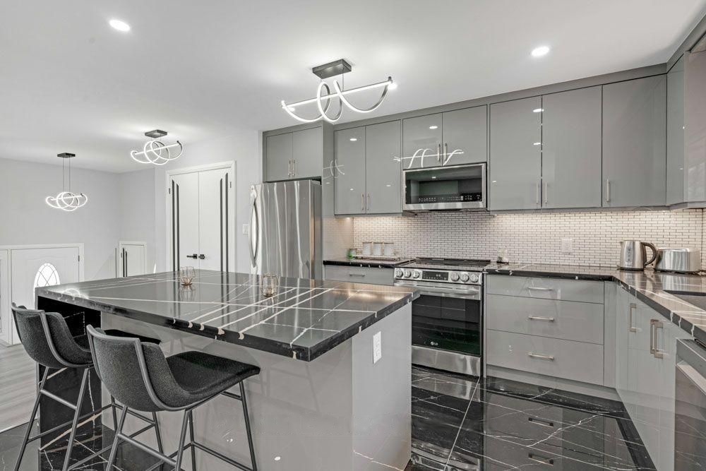 Renovated kitchen with grey high-gloss cabinets and a black marble-look island
