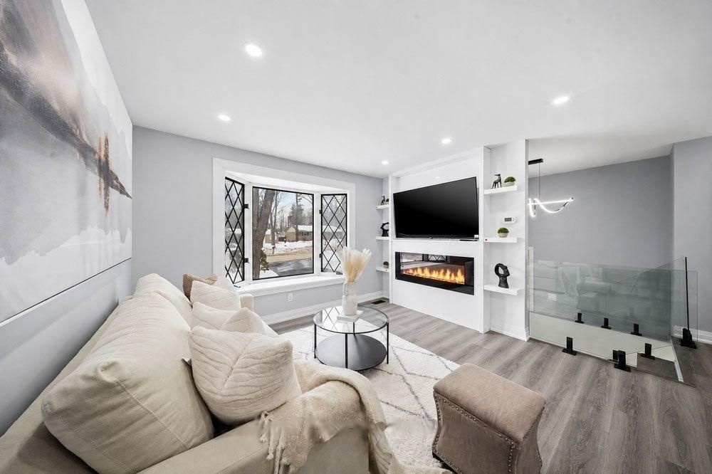 Living room with a bay window and a built-in fireplace wall