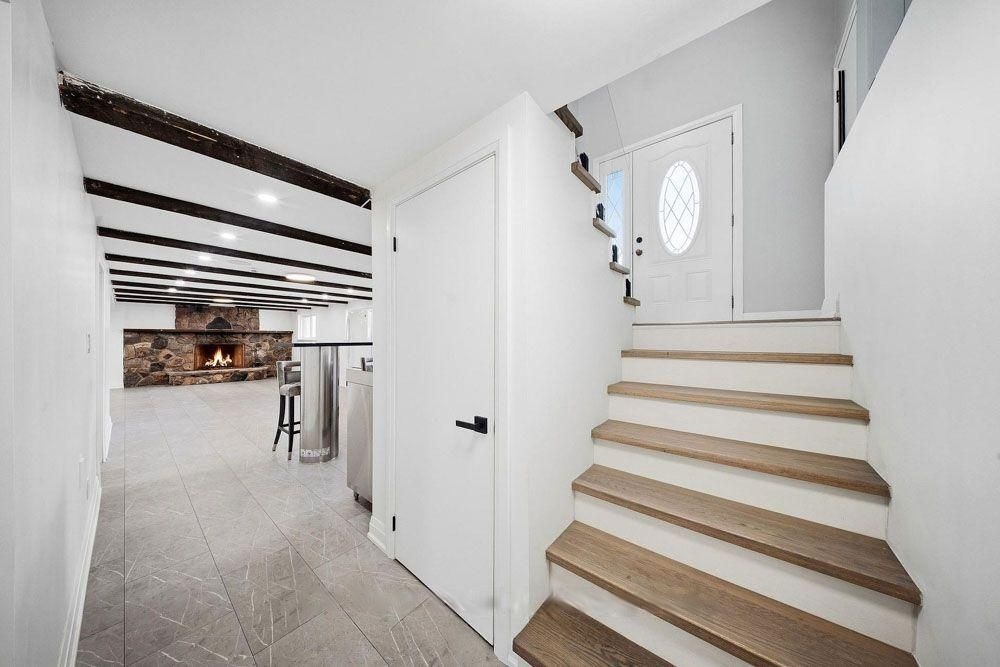 Stairs down to the lower level with a view of the stone fireplace